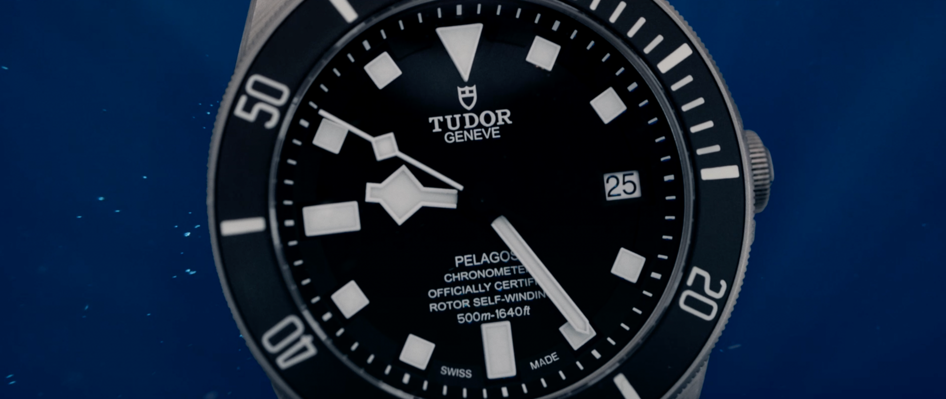 A tudor watch is sitting on a blue surface.