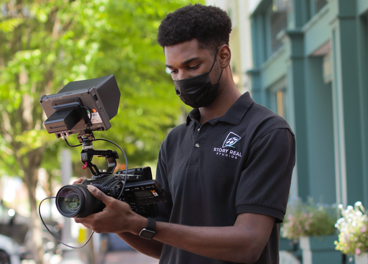 A man wearing a mask is holding a camera.