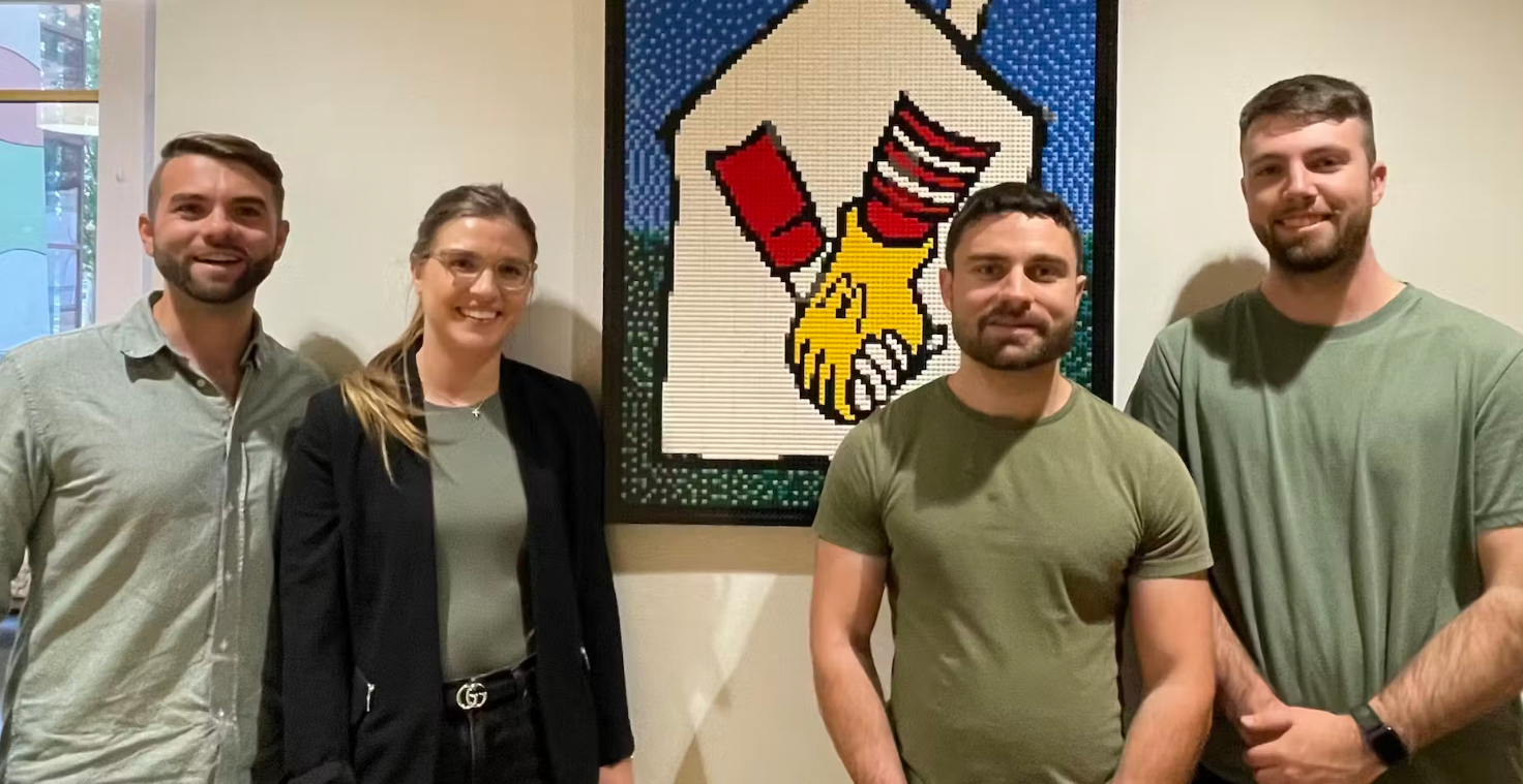 A group of people are standing next to each other in front of a painting.