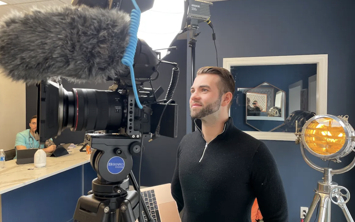 A man is standing in front of a camera in a room.
