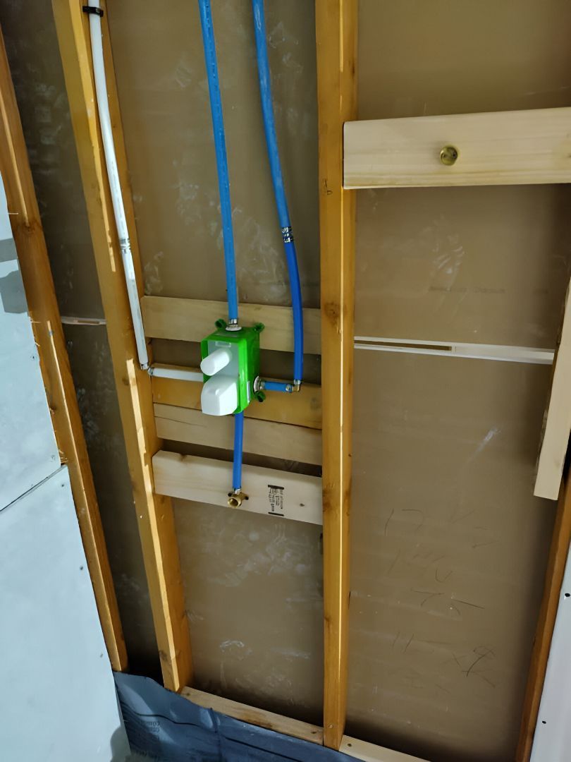 Exposed wall framing with a green electrical box and blue wiring installed between studs.