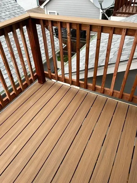 Wooden deck with railings overlooking neighboring houses and rooftops