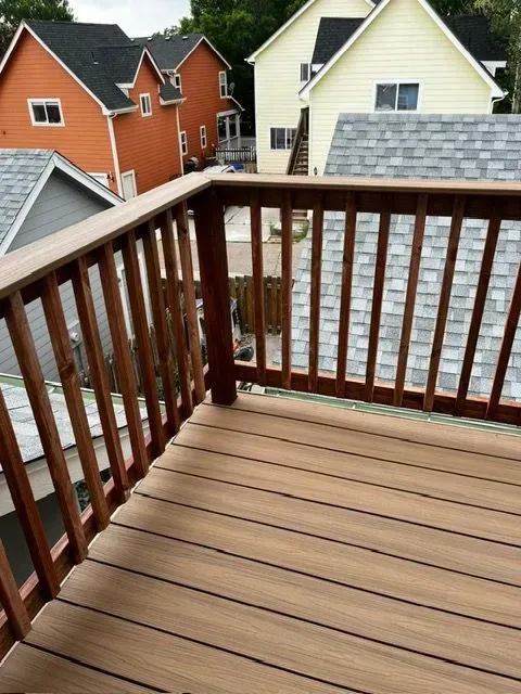Wooden balcony overlooking neighboring houses and rooftops on an overcast day