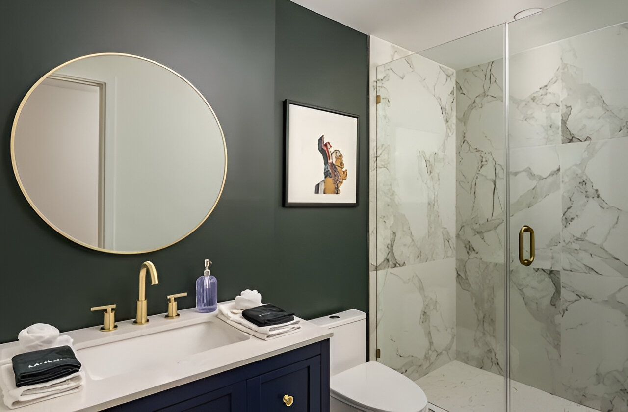 Modern bathroom with round mirror, white vanity, and marble glass shower.