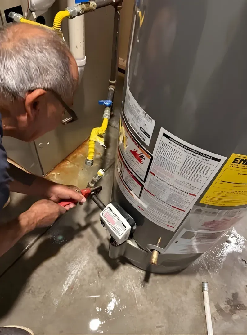 Technician adjusting a water heater gas line and fittings with tools in a utility room.