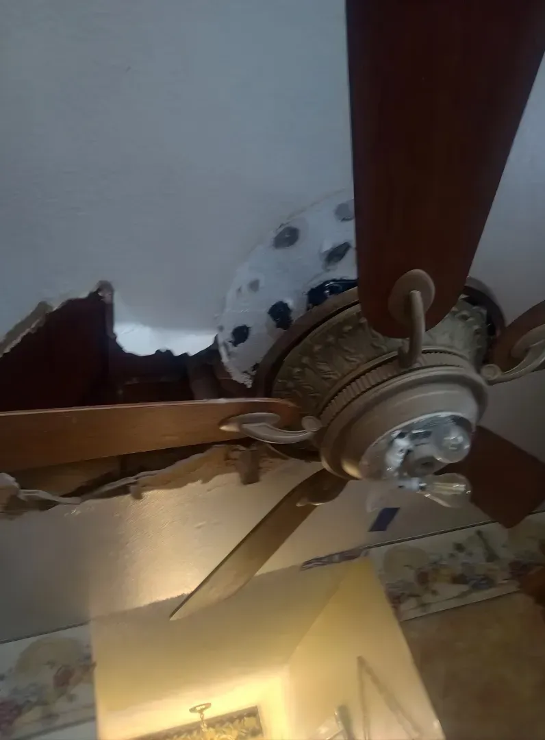 Damaged ceiling fan with broken blades hanging from a ceiling in a room