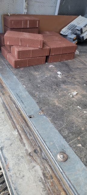 Stacked red bricks on a flatbed truck or trailer with metal side rails.