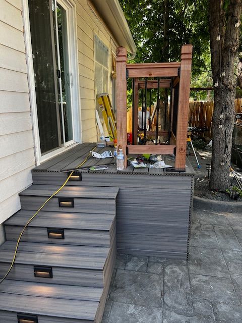 Back steps with yellow warning tape leading to a raised deck under construction beside a house
