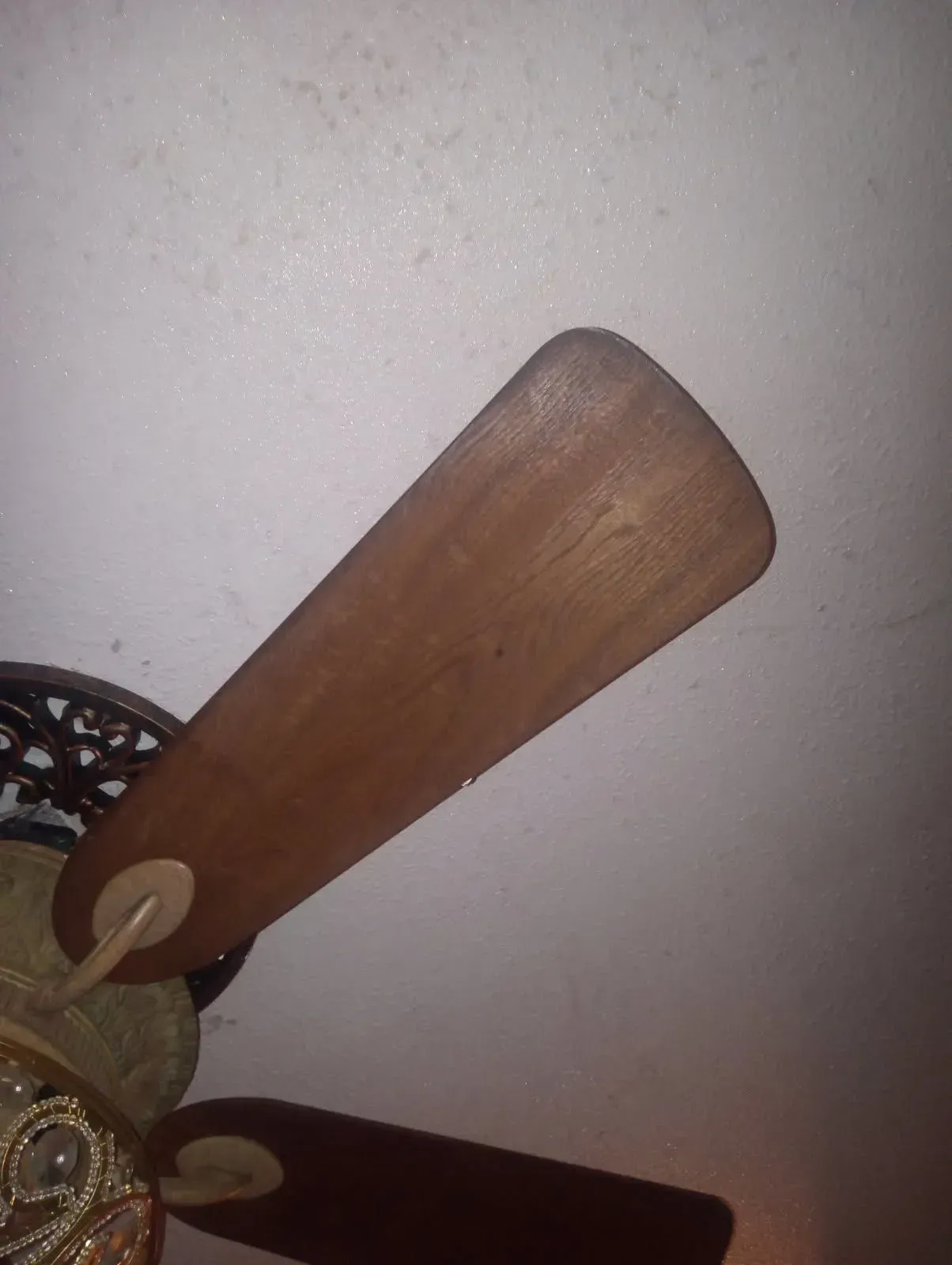 Ceiling fan with wooden blades against a light-colored ceiling.