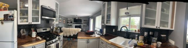 Bright kitchen with white cabinets, stainless appliances, and a long counter by a sunny window