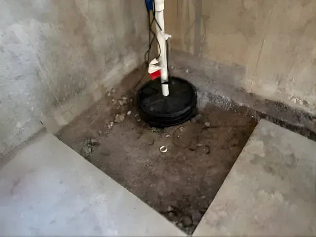 Corner with a black bucket holding a white pipe on a dirty concrete floor