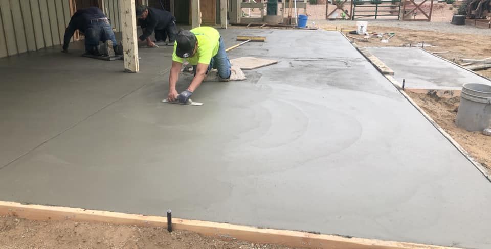 Worker smoothing fresh concrete on a patio slab at a construction site