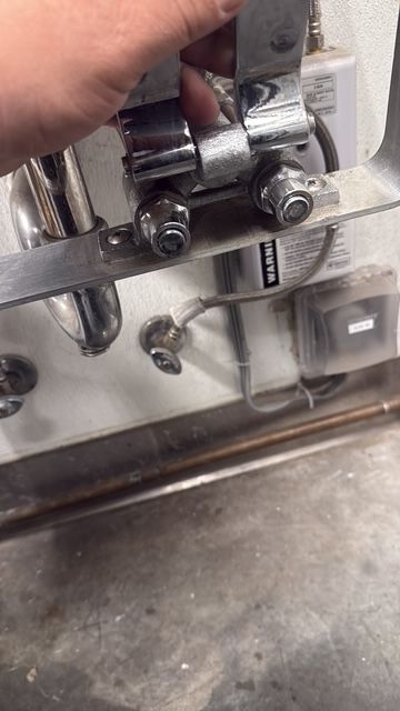 Close-up of metal hardware with bolts and brackets on a reflective machine panel.