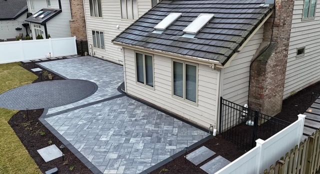 A house with a gray paved patio and curved walkway beside a fenced yard