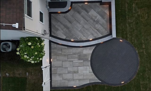 Overhead view of a backyard patio with gray stone pavers, a round table, and house exterior nearby