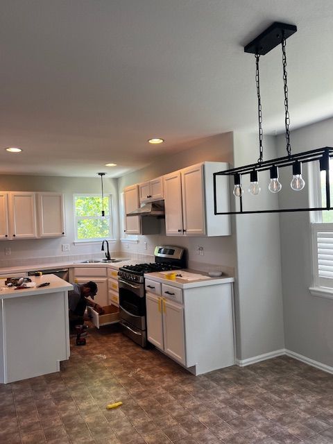 Bright kitchen with white cabinets, gray walls, patterned floor, island, and hanging light fixture