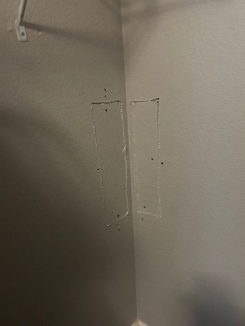 Close-up of a beige wall corner with two small rectangular cutouts or repair patches.