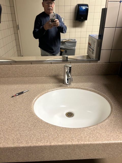 Bathroom sink and mirror, with a person taking a selfie in the reflection.