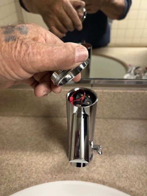Hand placing a chrome faucet aerator over a bathroom sink faucet