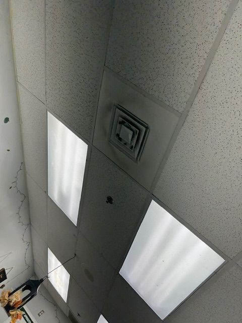 Ceiling tiles with fluorescent lights and air vents in an indoor room