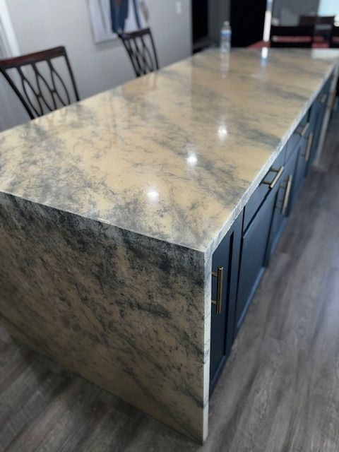Marble-top kitchen island with blue cabinets in a modern room