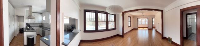 Bright empty living room with large arched windows, wood floors, and a fireplace on the left