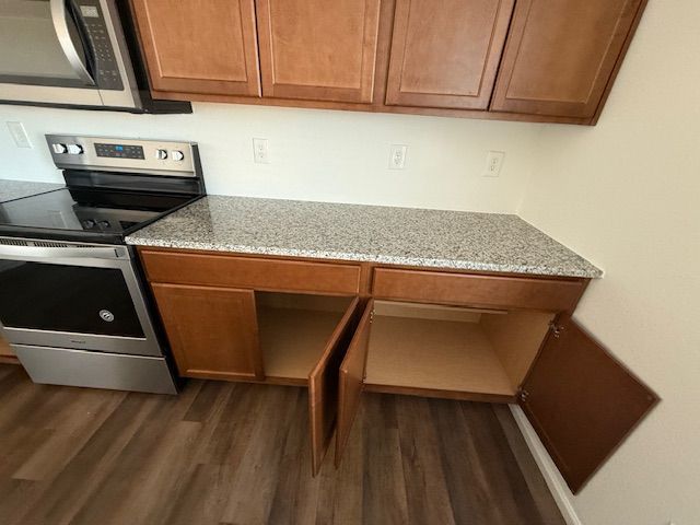Kitchen with stove and countertop, showing open cabinet and drawer space below.