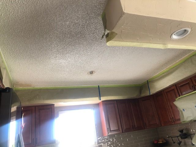 Kitchen with dark wood cabinets, bright window, and a textured ceiling under construction