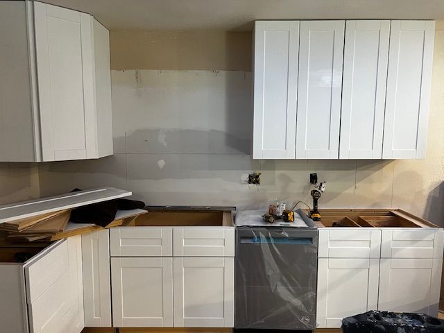 Kitchen under renovation with white cabinets, open countertop, and a dishwasher in the center