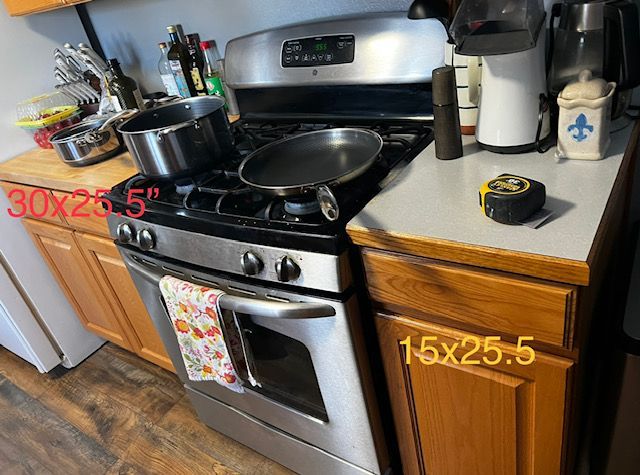 Kitchen stove and countertop with pans, white appliances, and wooden cabinets, marked with red measurements.