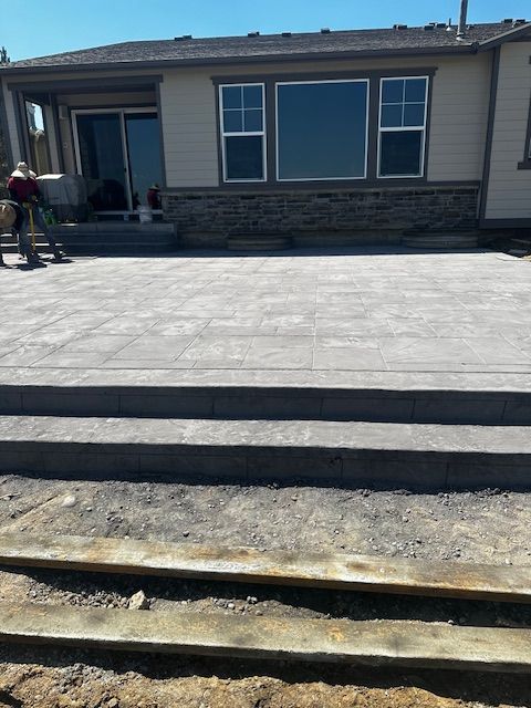 New concrete front walkway and steps leading to a house with stone facade and windows