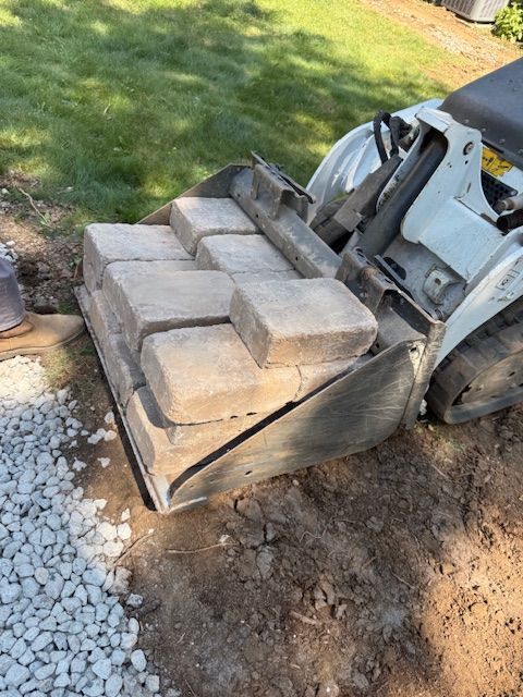 Bobcat with pallet of cinder blocks on a gravel and dirt yard