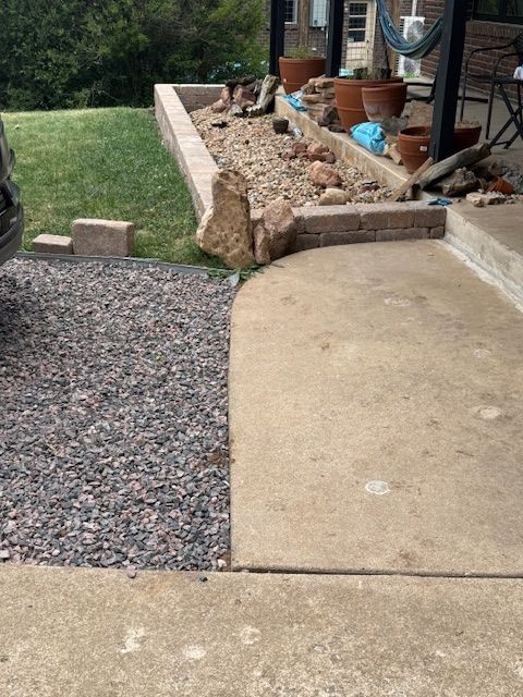 Front yard walkway and gravel path beside a raised garden bed with tools and pots
