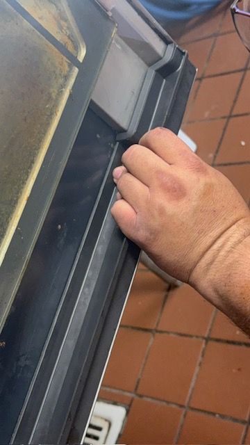 Hand opening a gray door lock on a tiled floor doorway
