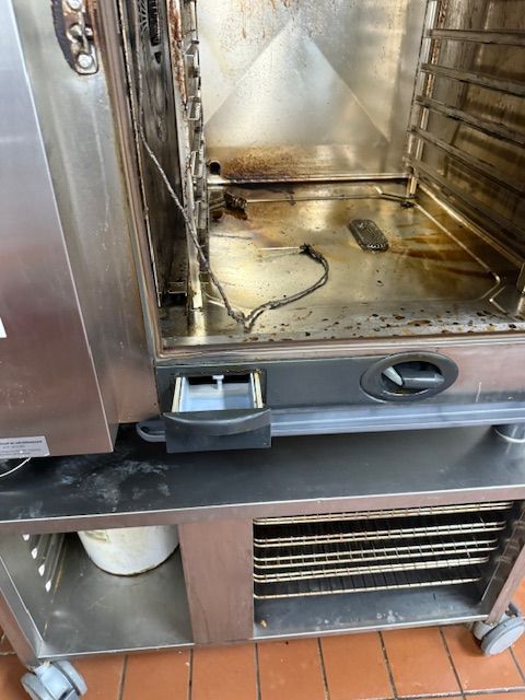 Stainless steel commercial oven with open door and dirty interior on a wheeled base