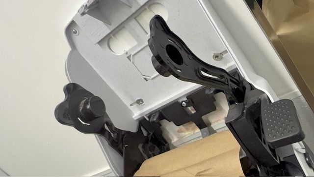 Close-up of a white mechanical device with black moving arms and a cardboard piece inside.