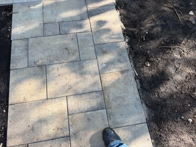 Paved sidewalk beside a dirt path, with a shoe visible at the bottom edge.