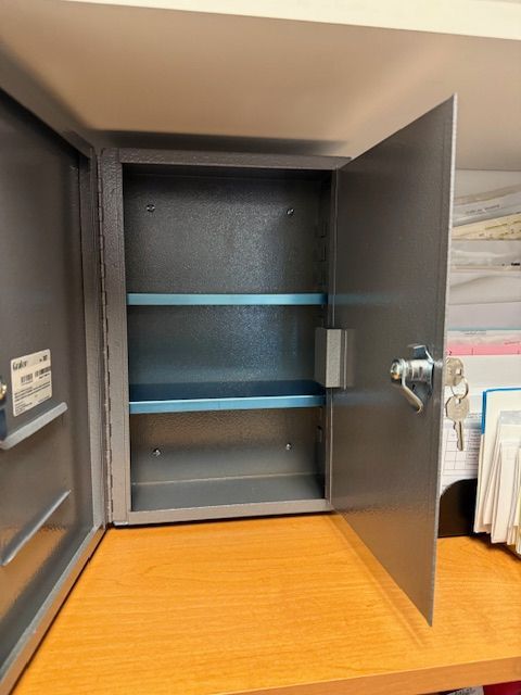 Open wall cabinet with gray doors and blue shelves on a wooden desk