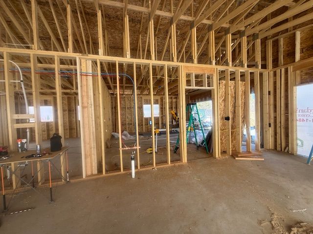 Interior of a house under construction with exposed wooden framing and unfinished walls