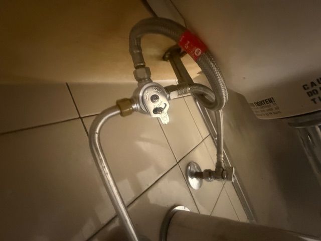 Close-up of a wall-mounted shower hose and valve in a tiled bathroom.