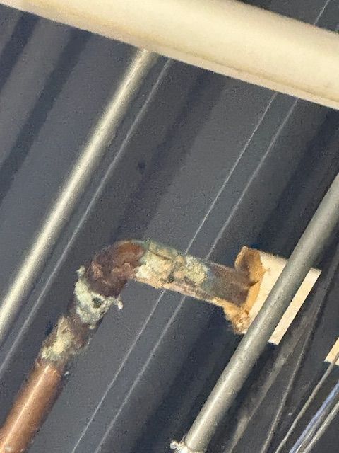 Close-up of a rusted metal pipe or railing against a gray corrugated background.