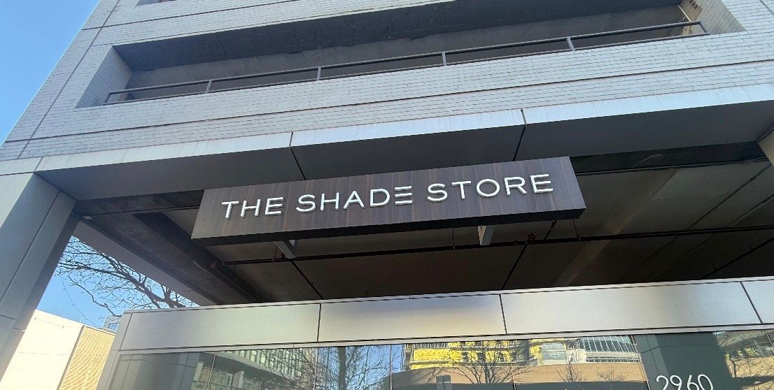 Storefront sign reading “THE SHADE STORE” on a modern building entrance.