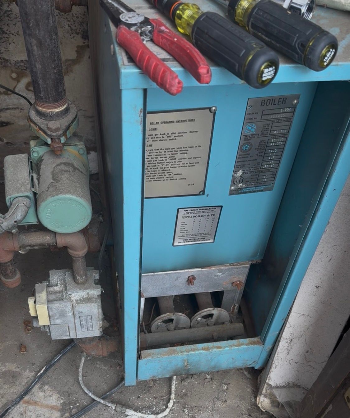 Blue electrical panel with labels and tools resting on top in a utility room