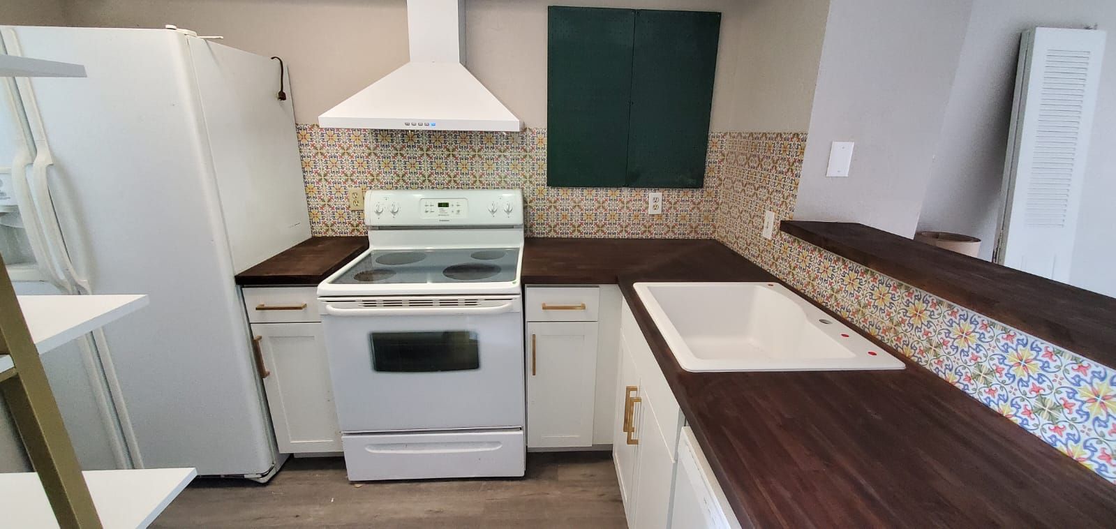 Compact kitchen with white appliances, dark countertops, and mosaic tile backsplash