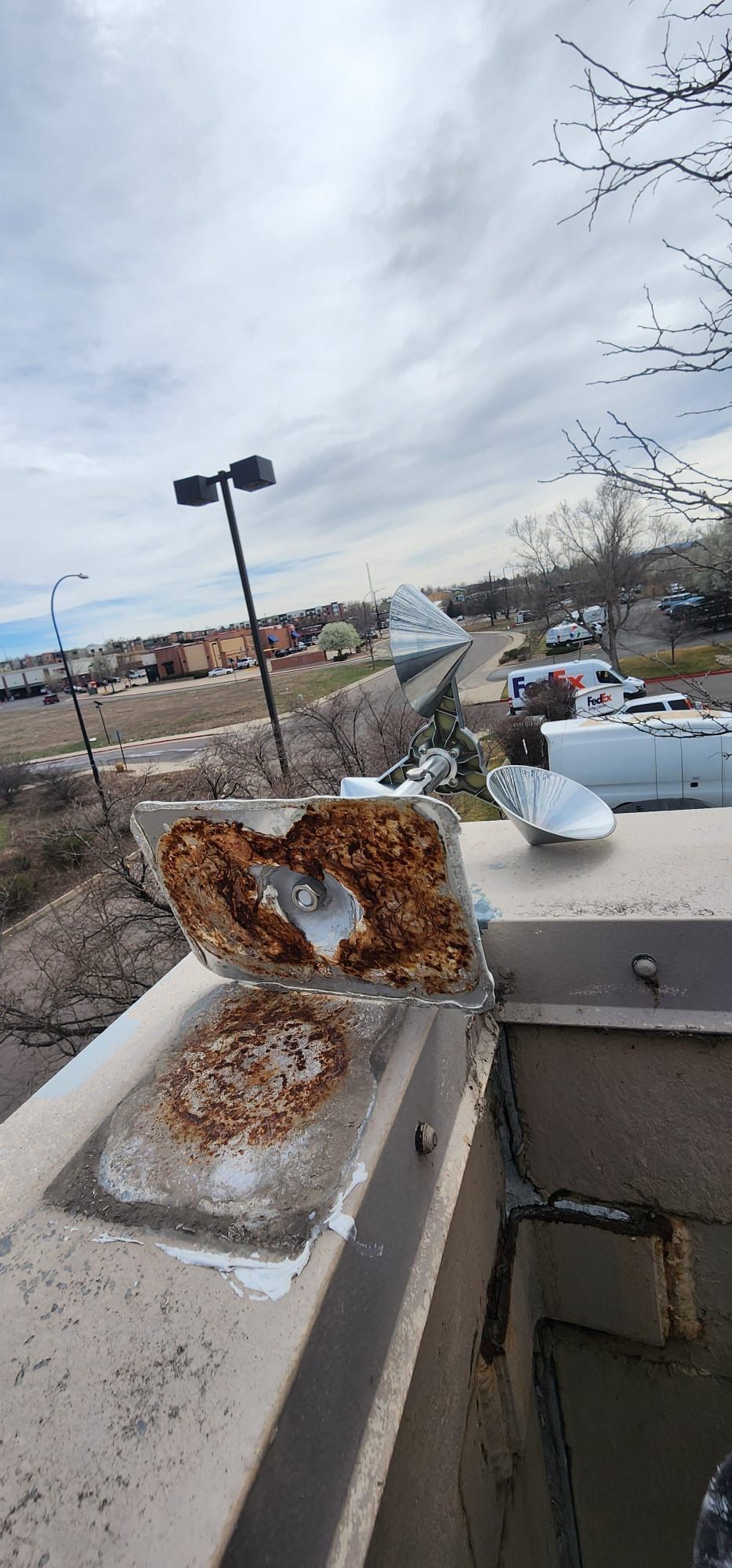 Rusty metal debris on a concrete ledge overlooking a cloudy outdoor urban scene
