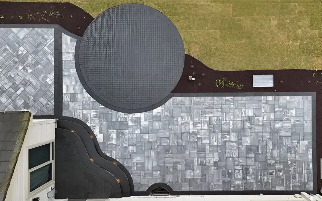 Aerial view of a house roof with a large round gray structure and a small skylight.