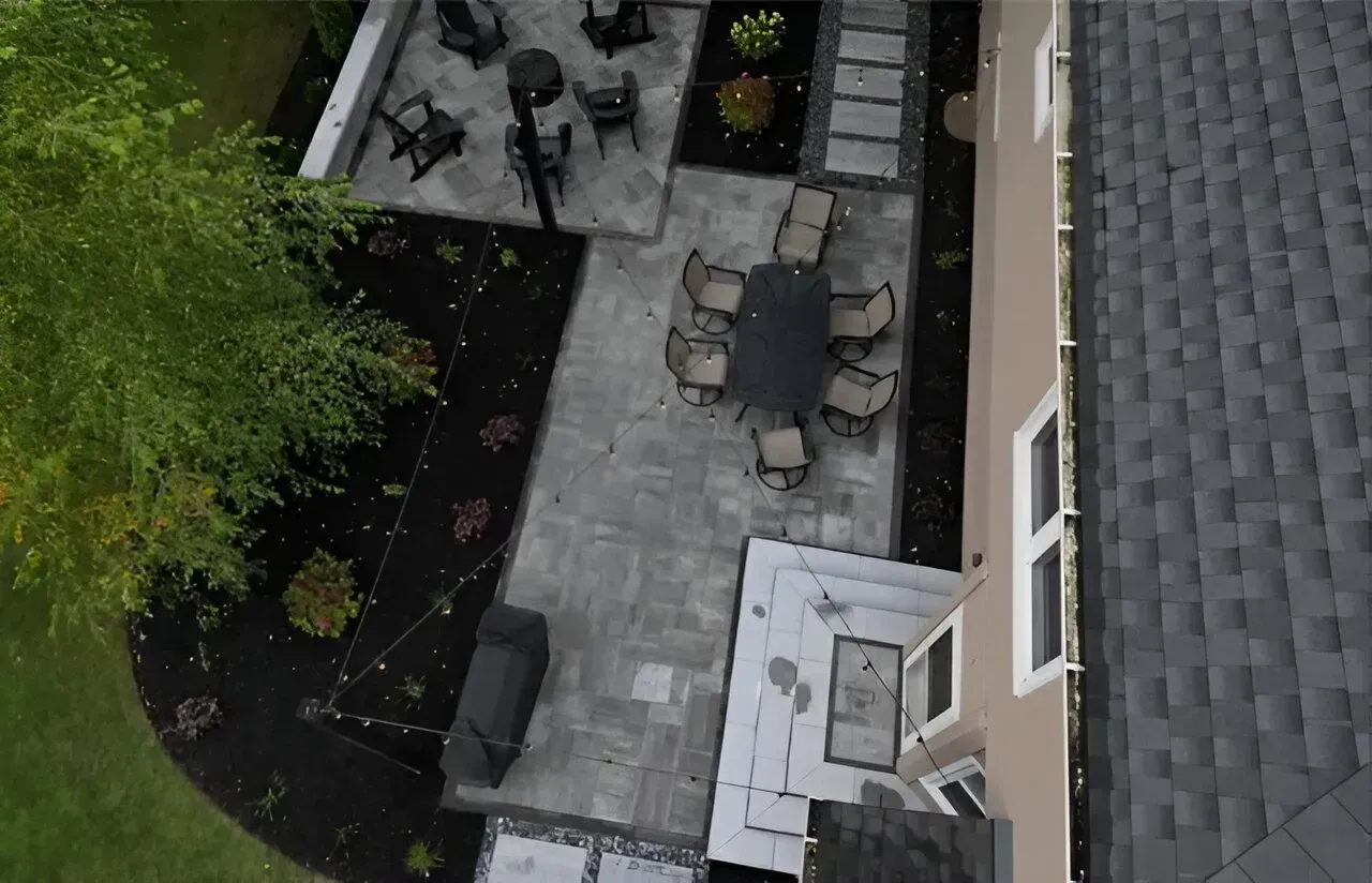 Overhead view of a backyard patio with outdoor furniture, potted plants, and a house wall.