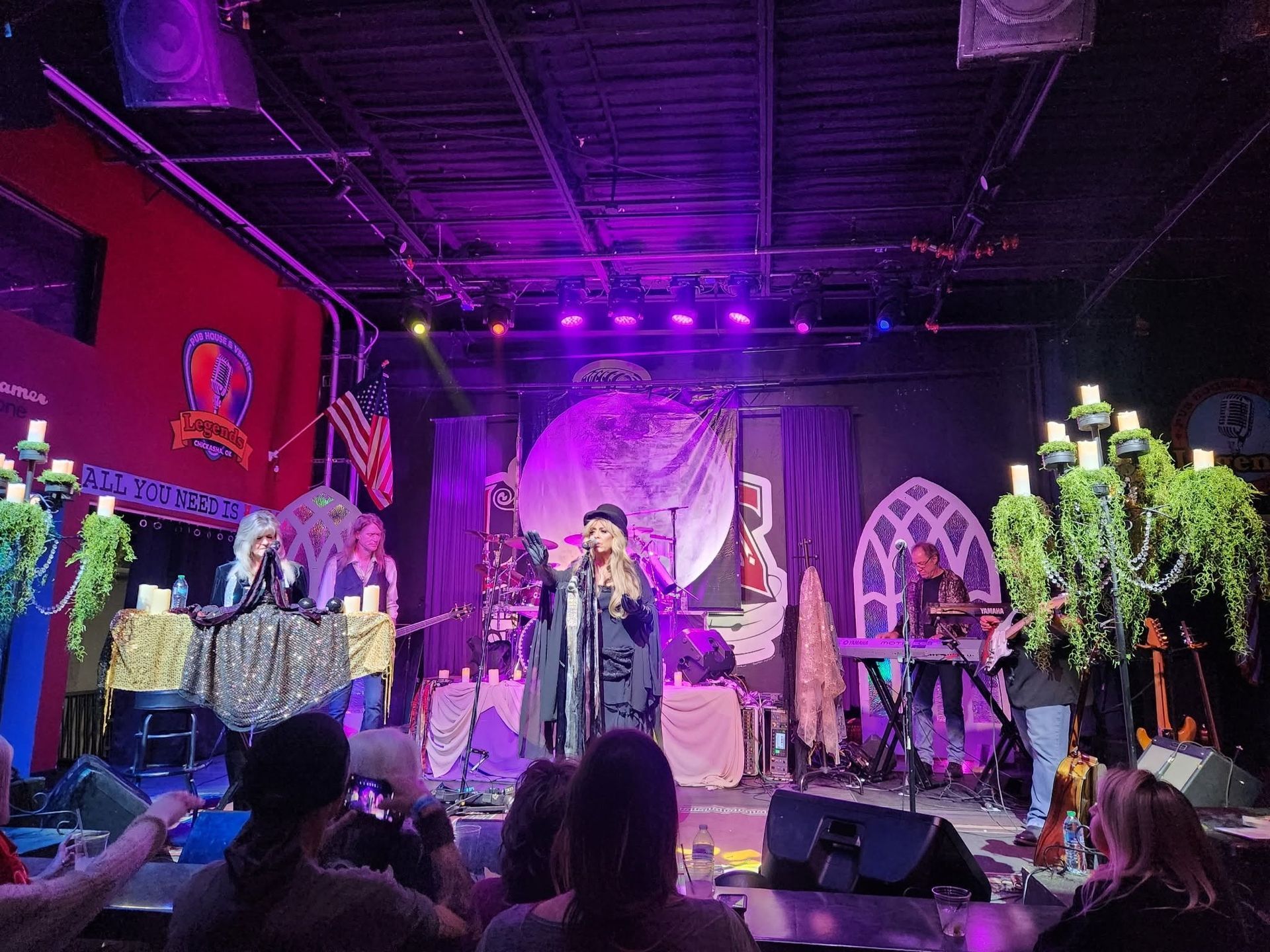 Purple-lit live band performing on stage with audience silhouettes in front