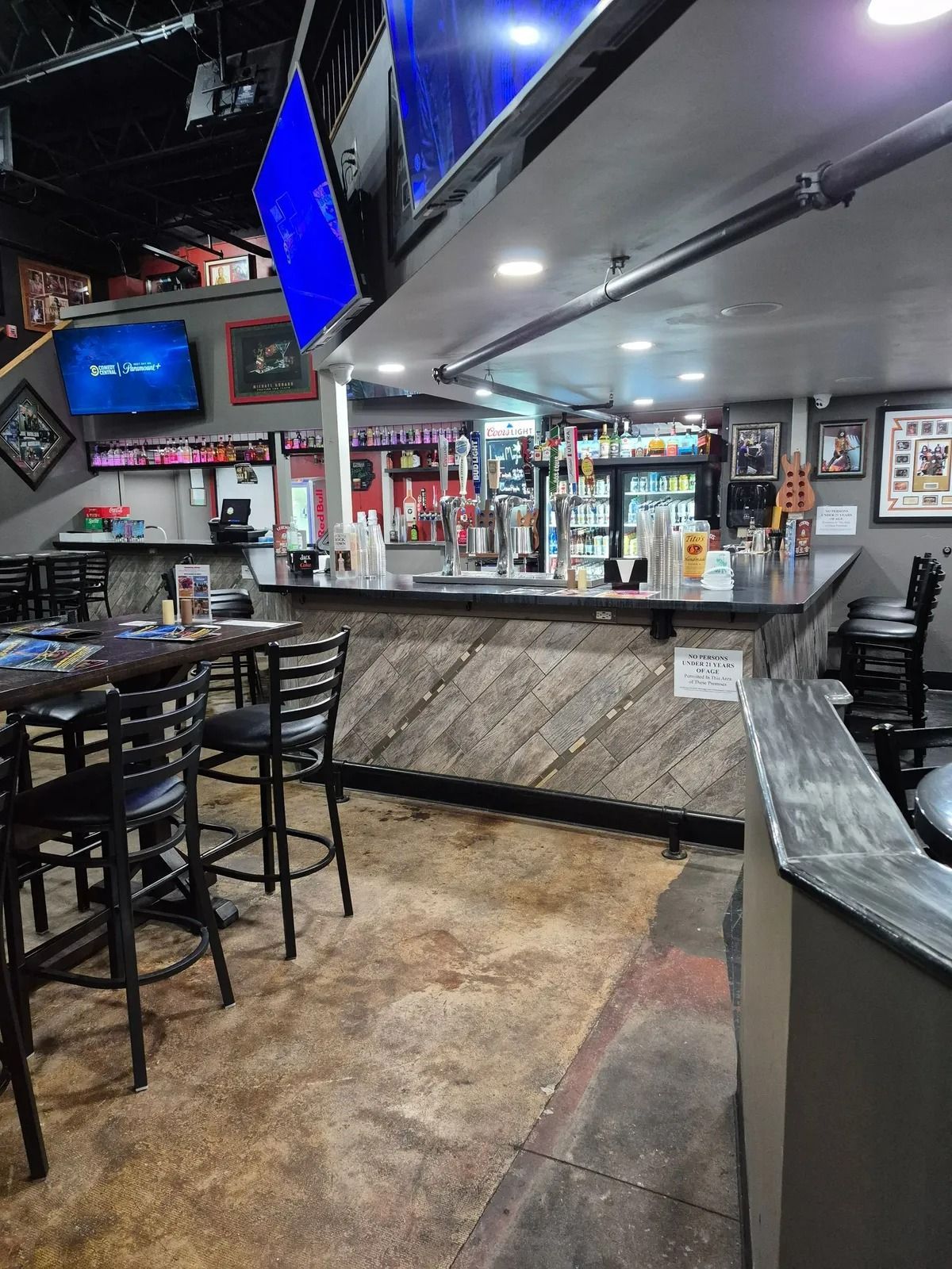 Empty sports bar interior with high stools, TVs, and a mirrored counter