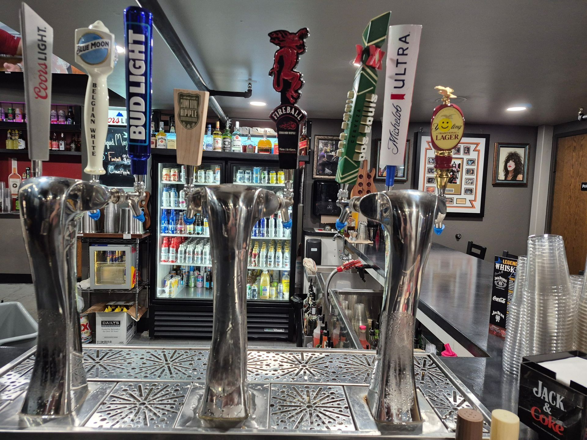 Bar with three chrome beer taps and rows of bottles behind the counter